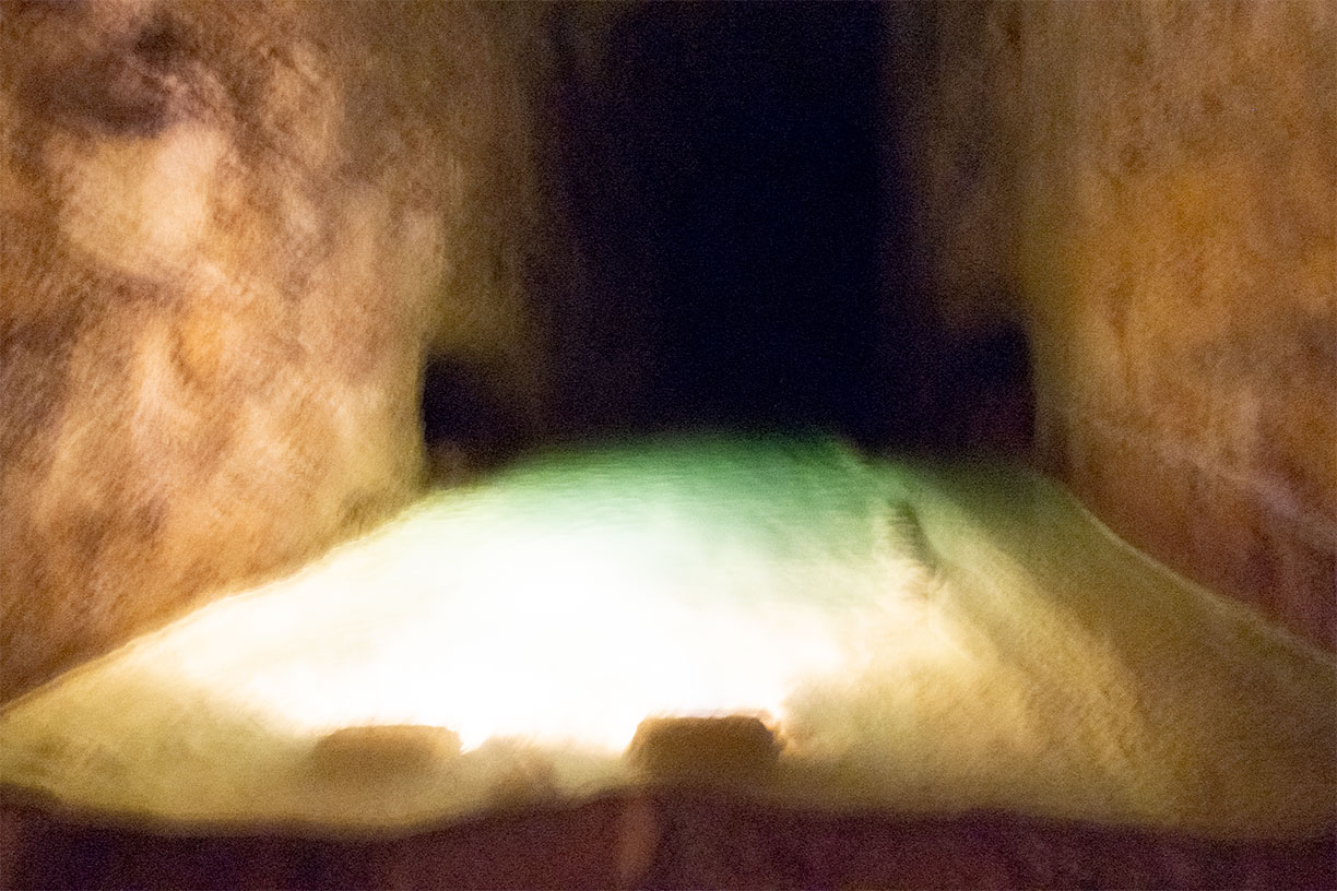 Abstract photo - illuminated water between cave walls, dark entry way